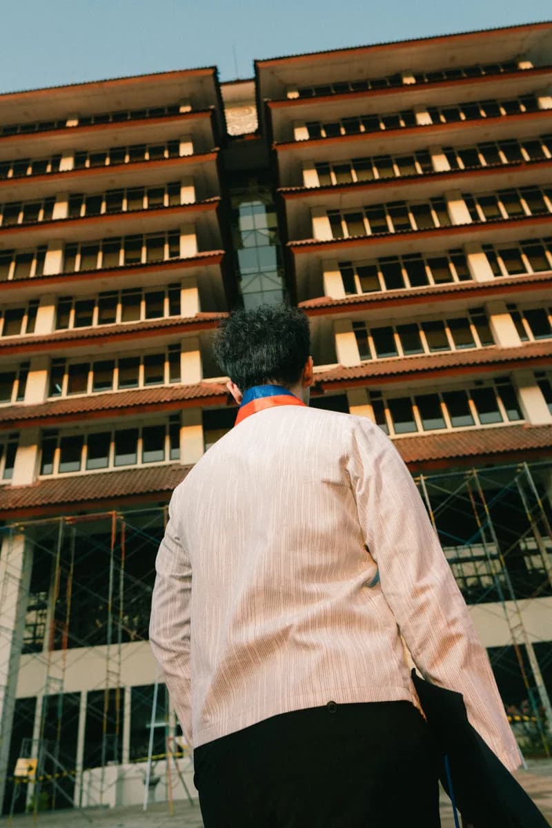 Wahyu walking outdoors beside a university building
