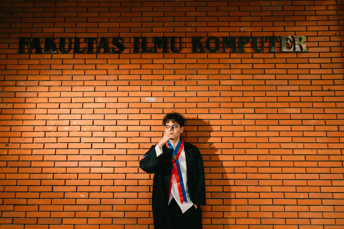 Wahyu standing near a brick faculty building