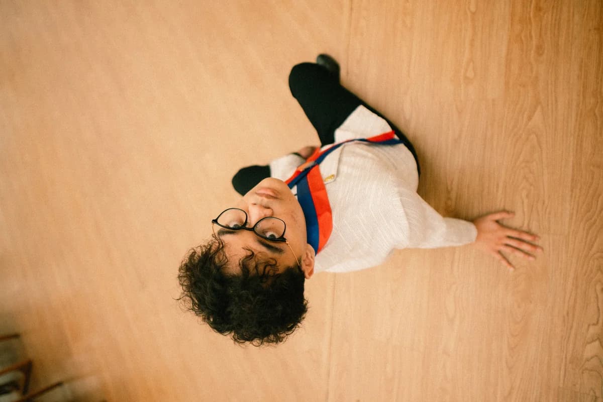 Wahyu sitting on a wooden floor, photographed from above