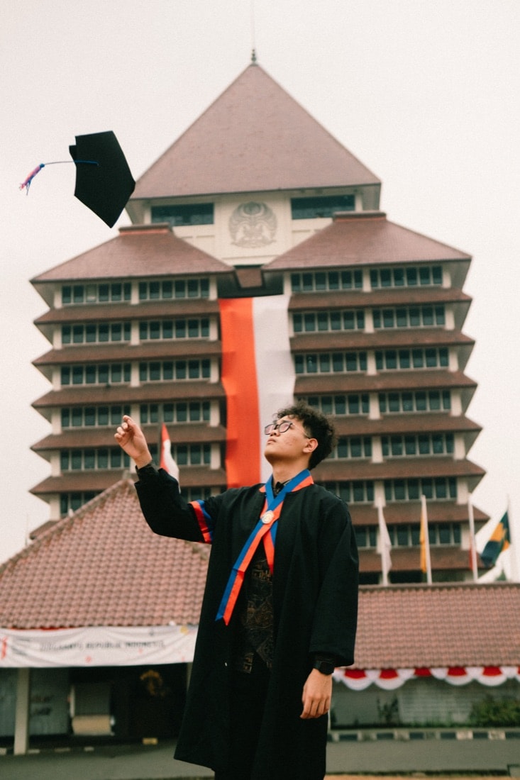Wahyu tossing his graduation cap in front of the Universitas Indonesia rectorate